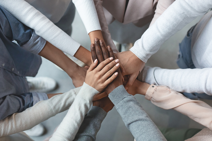 Close up of international business team showing unity with putting their hands together on top of each other. Concept of teamwork, top view